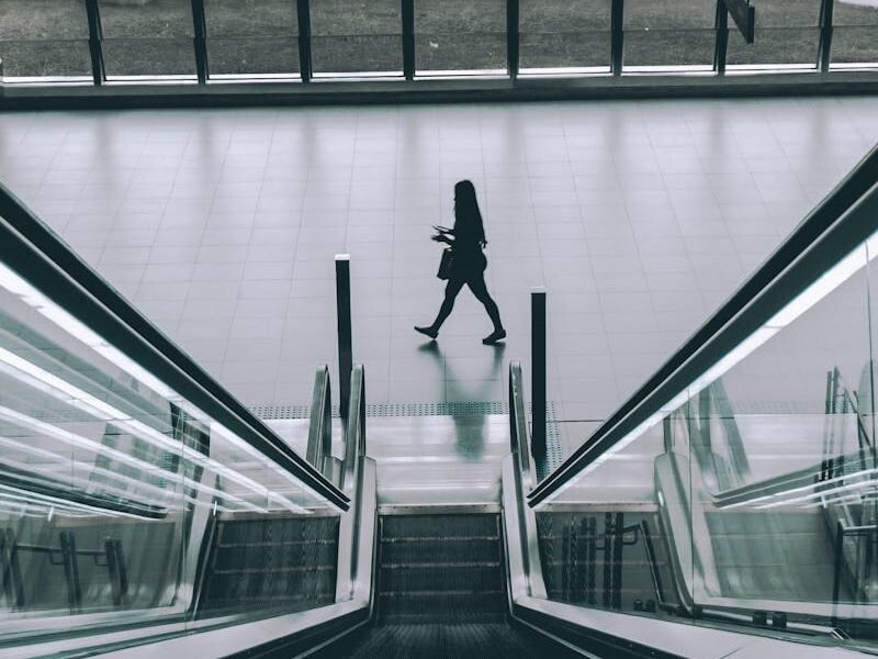 People using the sleek modern escalator in an indoor building with glass panels.